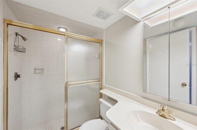 full bath featuring toilet, vanity, a stall shower, and visible vents