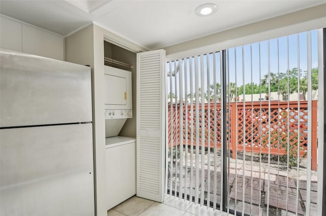 washroom with stacked washer / dryer, light tile patterned flooring, laundry area, and a wealth of natural light
