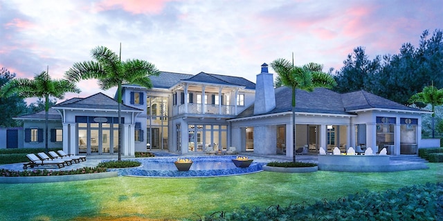 back of house with a balcony, french doors, a yard, and a patio area