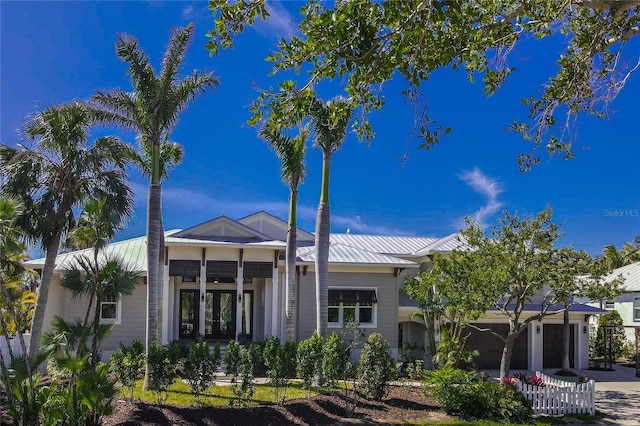 rear view of property featuring driveway, a standing seam roof, an attached garage, and metal roof
