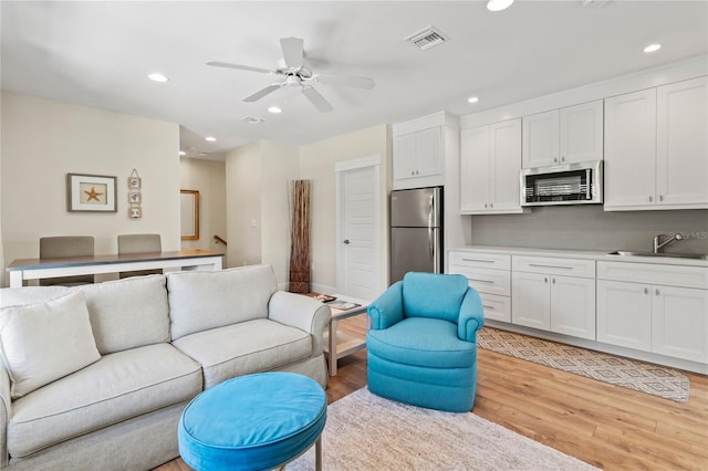 living room with a ceiling fan, visible vents, light wood finished floors, and recessed lighting