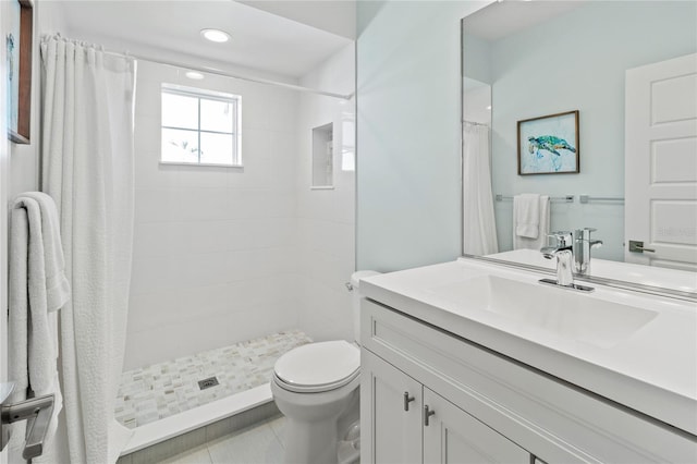 bathroom with vanity, toilet, tile patterned flooring, and tiled shower