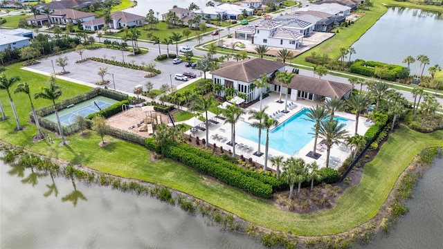 aerial view of residential area with a pool and a large body of water