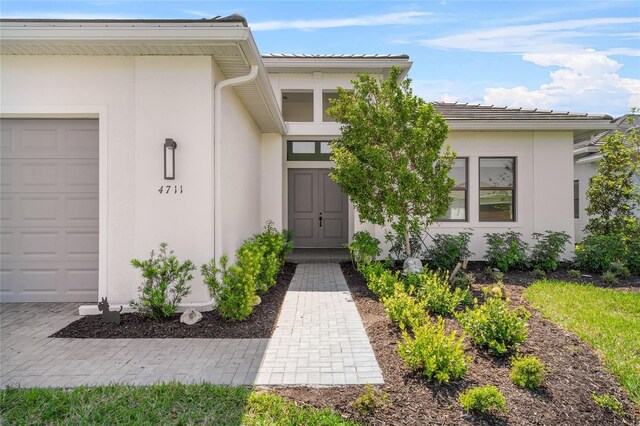 entrance to property featuring stucco siding, a garage, and a tiled roof