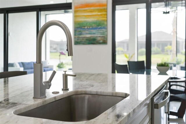 kitchen view of light stone counters, a sink, and dishwasher
