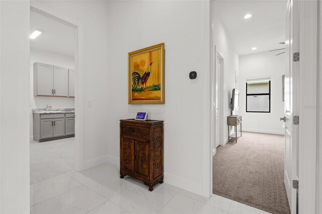 hallway with baseboards, recessed lighting, light carpet, and light marble finish flooring