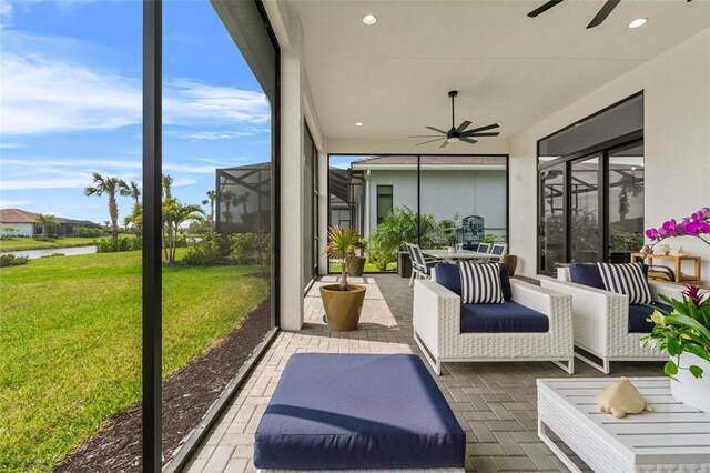 sunroom / solarium with ceiling fan and a water view