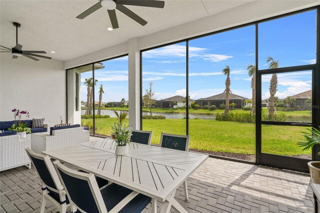 sunroom / solarium with a ceiling fan, a water view, and outdoor dining space