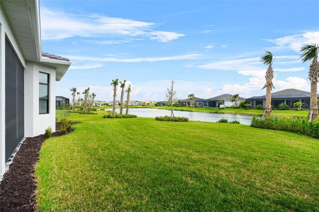 view of grassy yard featuring a residential view and a water view