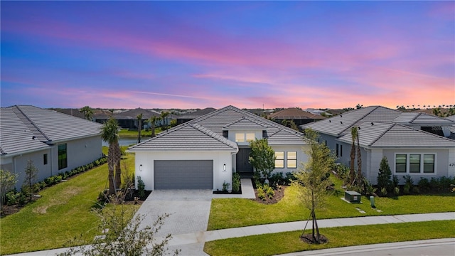 view of front facade with an attached garage, concrete driveway, stucco siding, a front lawn, and a tiled roof