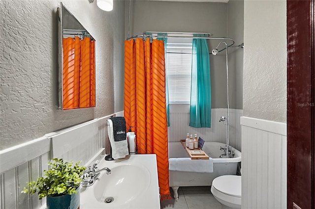 501 Washington Ave, Eustis, FL 32726 - bathroom featuring toilet, a sink, wainscoting, a freestanding bath, and a textured wall