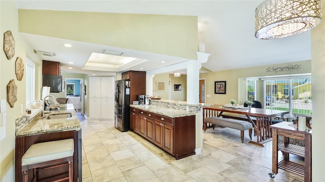 kitchen featuring a sink, freestanding refrigerator, recessed lighting, and light stone countertops