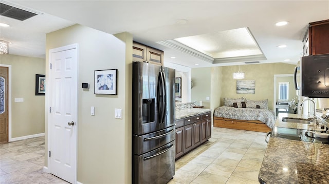 kitchen with visible vents, baseboards, open floor plan, stainless steel fridge, and a sink