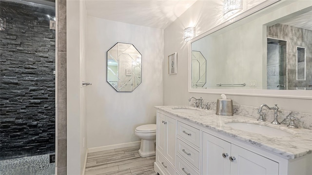 full bathroom with a sink, baseboards, toilet, and double vanity