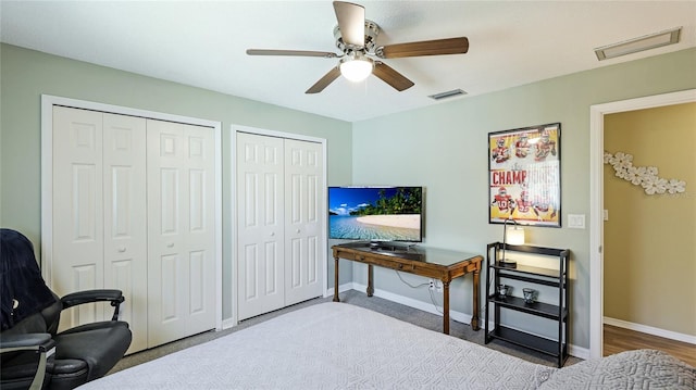 bedroom featuring ceiling fan, multiple closets, visible vents, and baseboards