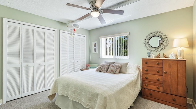 bedroom with ceiling fan, multiple closets, and carpet