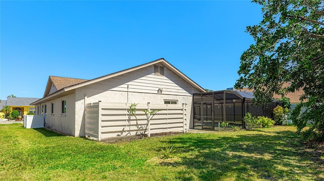 view of side of home with a lawn, glass enclosure, and stucco siding