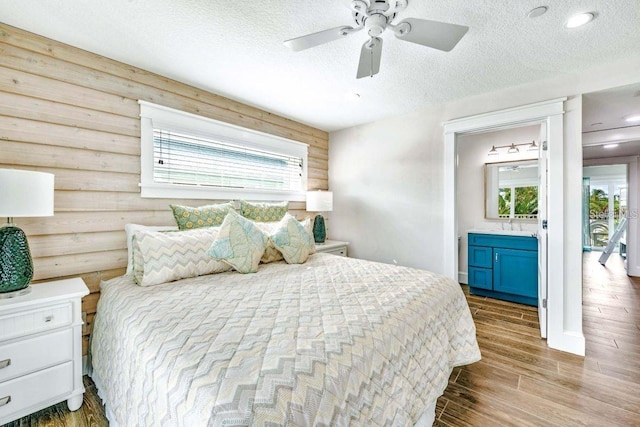 336 Avenida De Mayo, Sarasota, FL 34242 - bedroom with ensuite bath, a textured ceiling, wood finished floors, and a ceiling fan