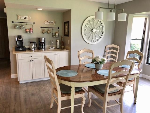 dining room with baseboards, bar area, and wood finished floors