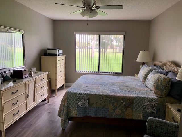 bedroom with dark wood-style flooring, a textured ceiling, and ceiling fan