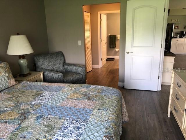 bedroom with baseboards and dark wood-type flooring