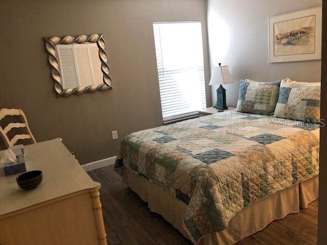 bedroom with baseboards and dark wood finished floors