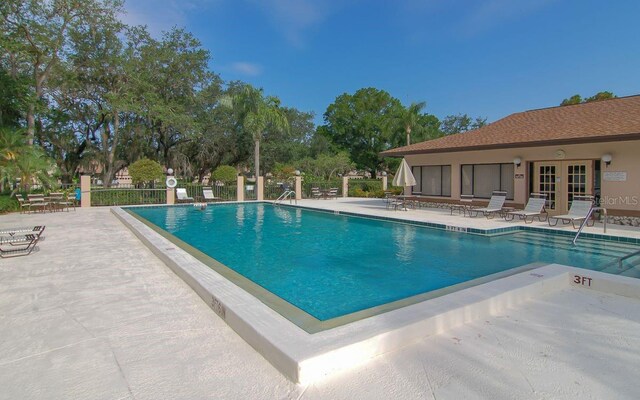 pool with a patio area, fence, and french doors