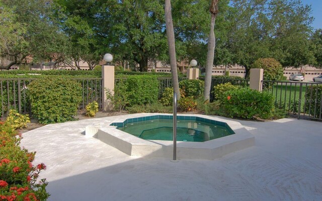 view of swimming pool with a community hot tub and fence