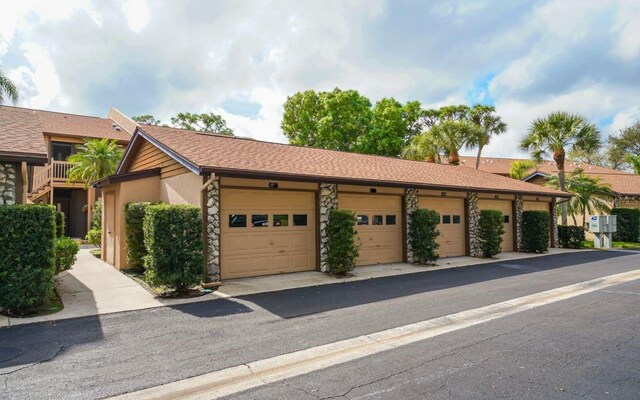single story home featuring stucco siding, stone siding, and community garages