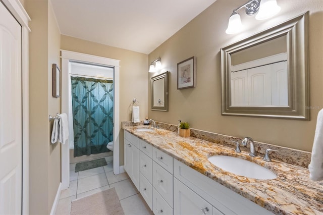 bathroom with toilet, double vanity, a sink, and tile patterned flooring