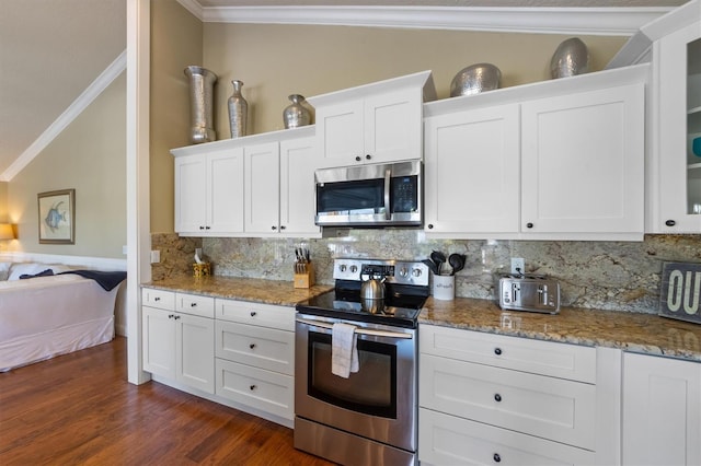 kitchen featuring crown molding, white cabinets, lofted ceiling, stainless steel appliances, and decorative backsplash