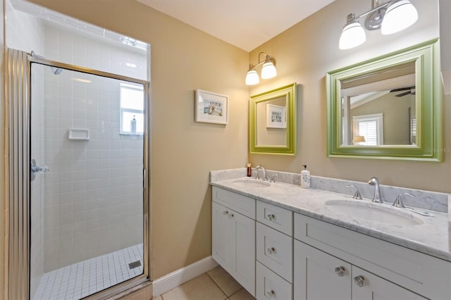 full bath featuring a stall shower, double vanity, a sink, and tile patterned flooring