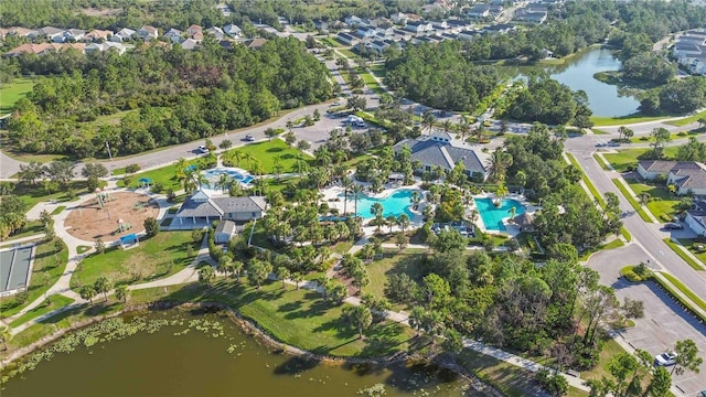 aerial view of property and surrounding area with a pool, a nearby body of water, and nearby suburban area
