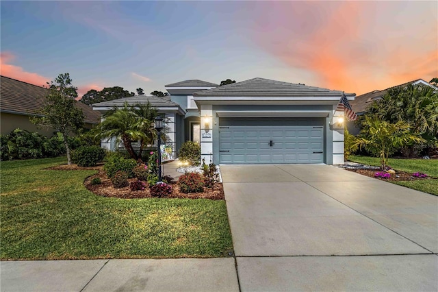 single story home with stucco siding, a yard, driveway, and an attached garage