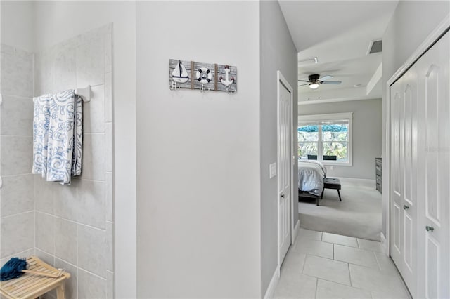 corridor featuring light tile patterned floors, light colored carpet, and baseboards