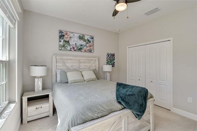 carpeted bedroom featuring a closet, baseboards, multiple windows, and ceiling fan