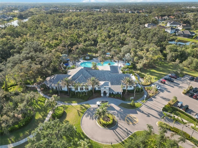 aerial view of property and surrounding area with a pool and a forest