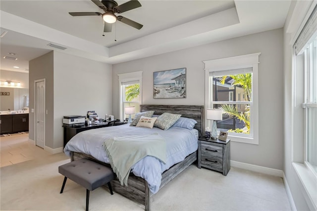 bedroom featuring light colored carpet, baseboards, multiple windows, and a raised ceiling
