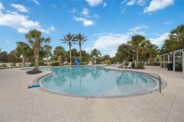 community pool with a water slide and a patio