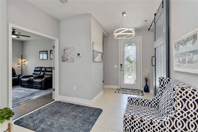 foyer with light tile patterned floors, baseboards, a chandelier, and ceiling fan