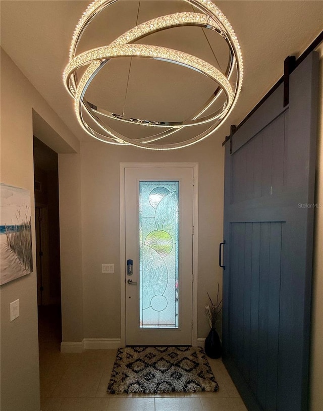 tiled entryway with a barn door and baseboards