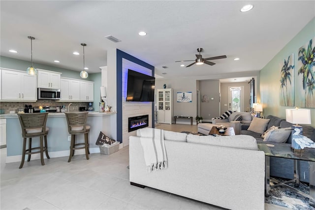 living area featuring ceiling fan, light tile patterned floors, a large fireplace, recessed lighting, and baseboards