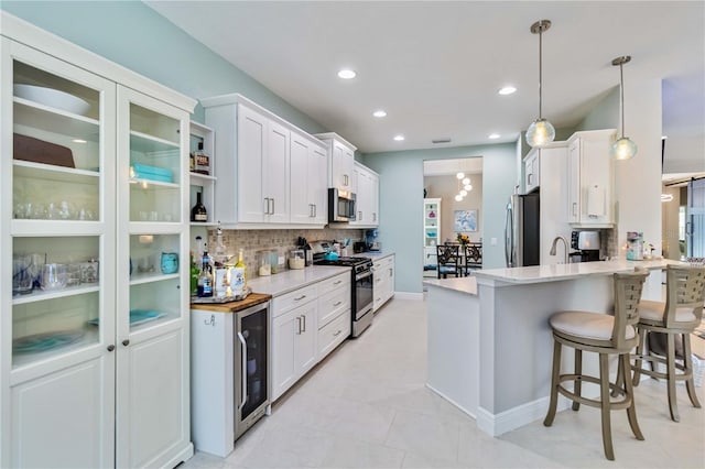 kitchen with appliances with stainless steel finishes, decorative backsplash, white cabinets, a peninsula, and recessed lighting