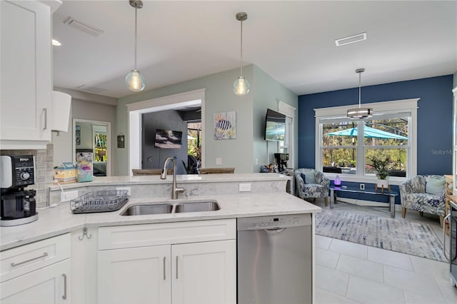 kitchen with stainless steel dishwasher, a sink, open floor plan, a peninsula, and white cabinetry