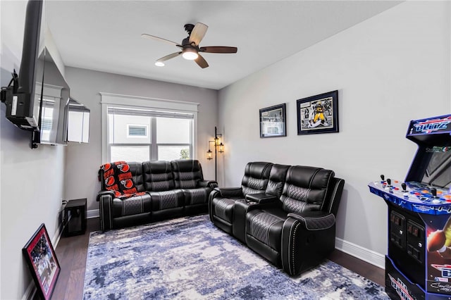 living area featuring a ceiling fan, baseboards, and wood finished floors