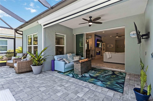view of patio featuring an outdoor living space with a fire pit, a ceiling fan, and a lanai