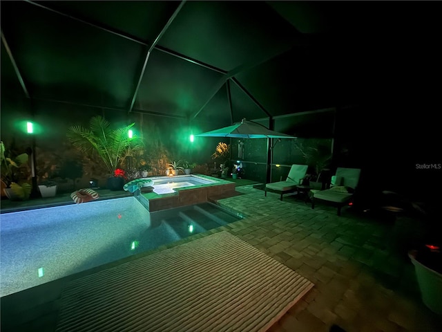 pool at night featuring a patio, an in-ground hot tub, a lanai, and an outdoor pool