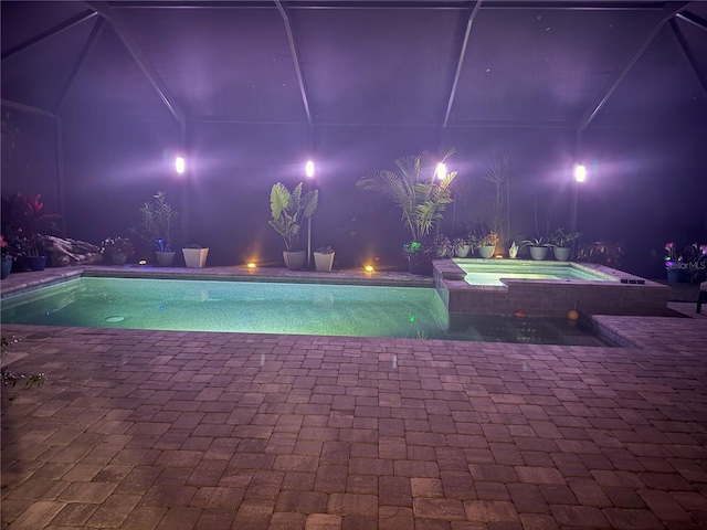 pool at twilight with a patio and a pool with connected hot tub