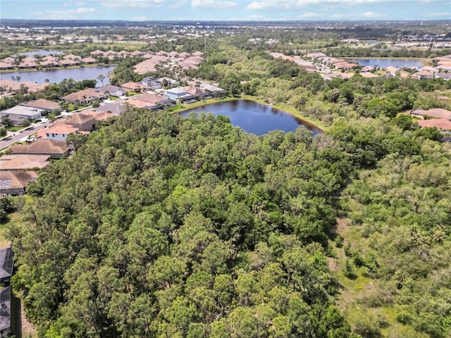 aerial view of property's location with nearby suburban area, a nearby body of water, and a heavily wooded area