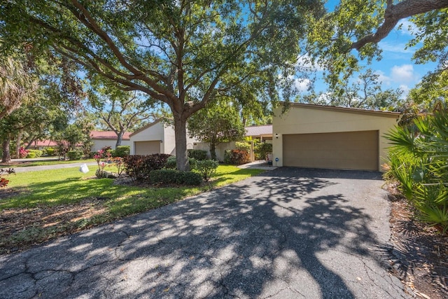 view of front of property featuring a garage, a front yard, stucco siding, and aphalt driveway